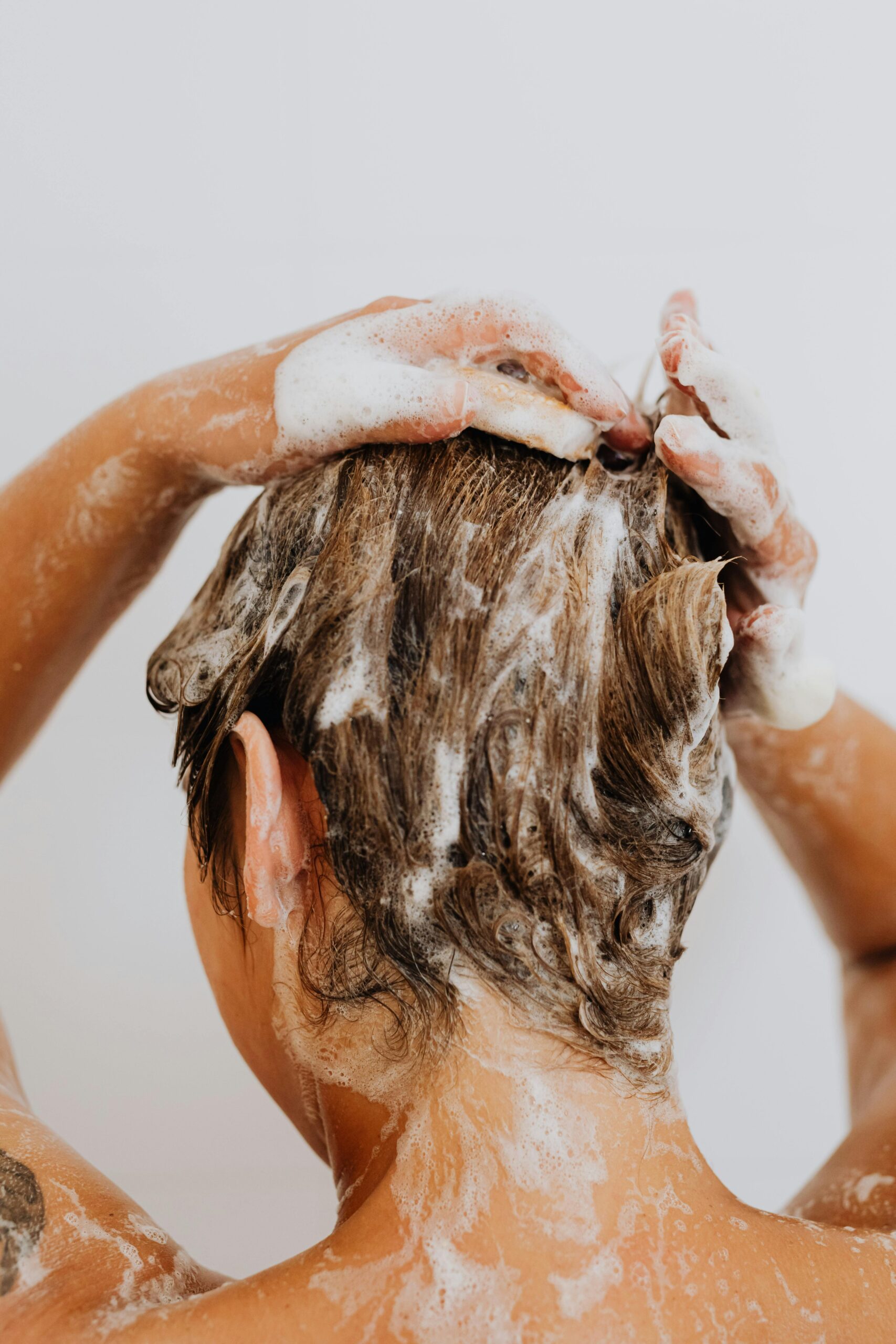 Femme appliquant du shampoing doux sur ses cheveux - Routine capillaire naturelle